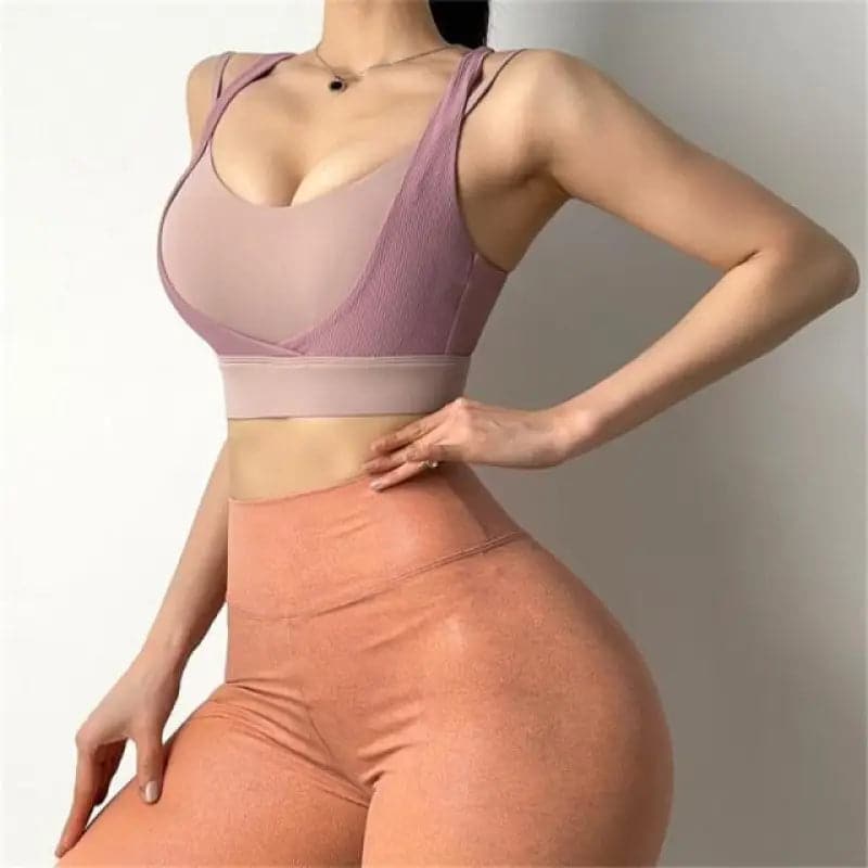 Femme portant un soutien-gorge de sport rose et un legging orange à taille haute.