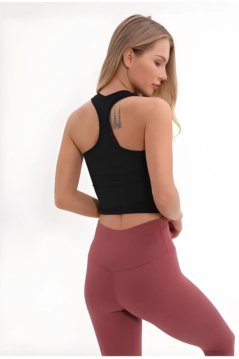 Femme portant un crop top noir et un legging bordeaux, vue de dos.