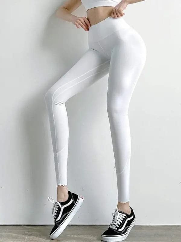 Leggings blancs à taille haute portés avec des baskets noires et blanches.