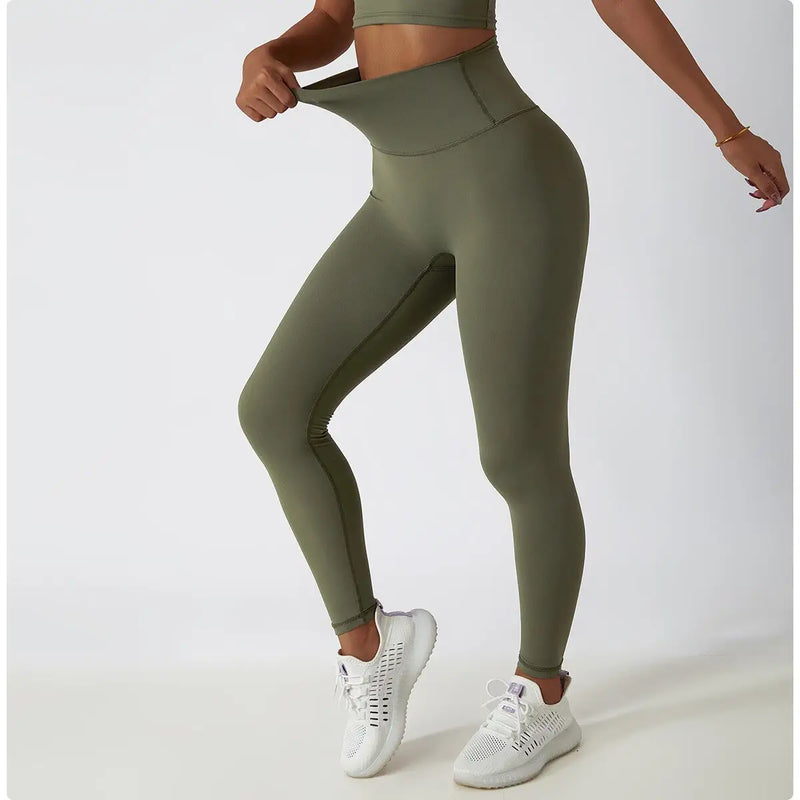 Leggings de sport vert olive à taille haute portés avec des baskets blanches.