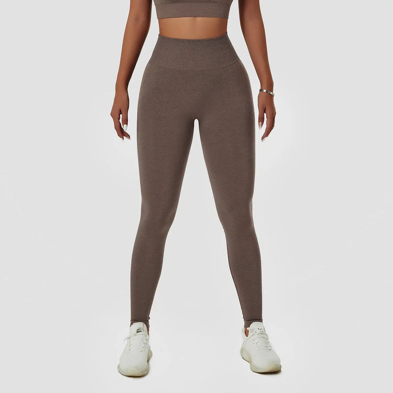 Leggings marron taille haute portés avec des baskets blanches.