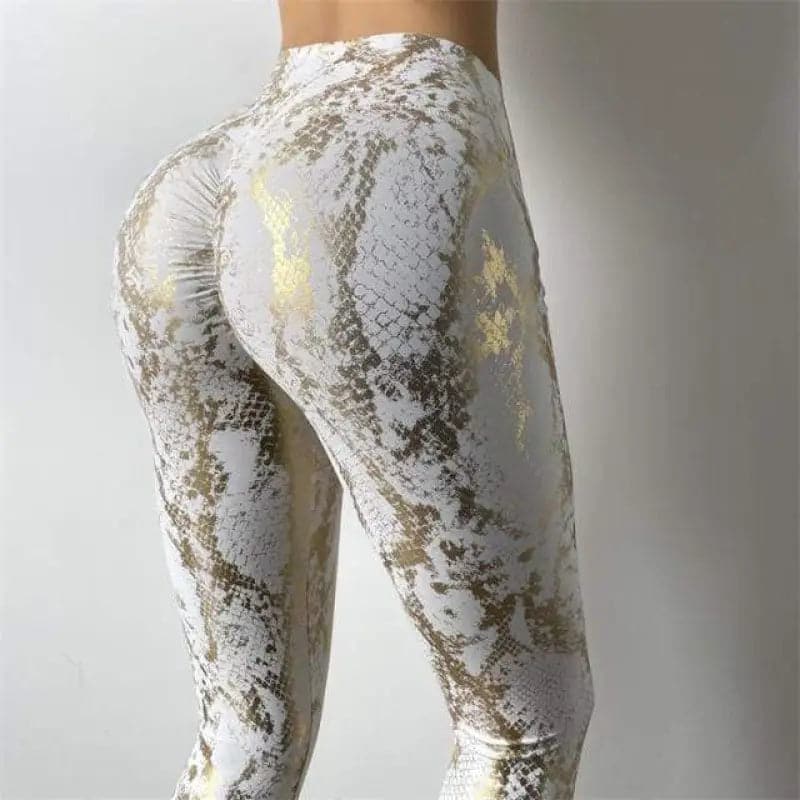 Des leggings ou des pantalons de yoga à motifs blancs et dorés qui mettent en valeur le bas du corps de la personne qui les porte.