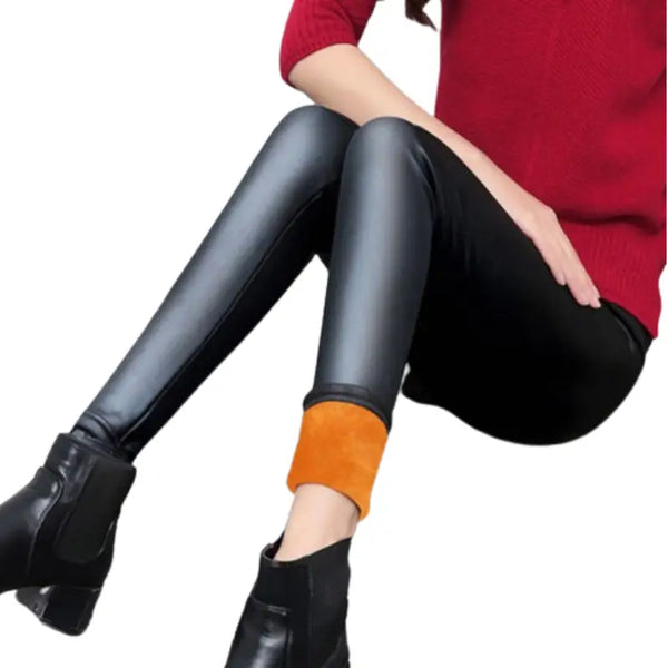 Une paire de leggings ou de pantalons moulants noirs brillants portés avec des chaussettes orange et des bottines noires.